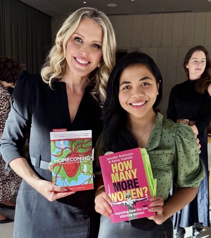 Ratu Nida holding How Many More Women? beside Jennifer Robinson holding Homecoming at a women’s justice and storytelling event